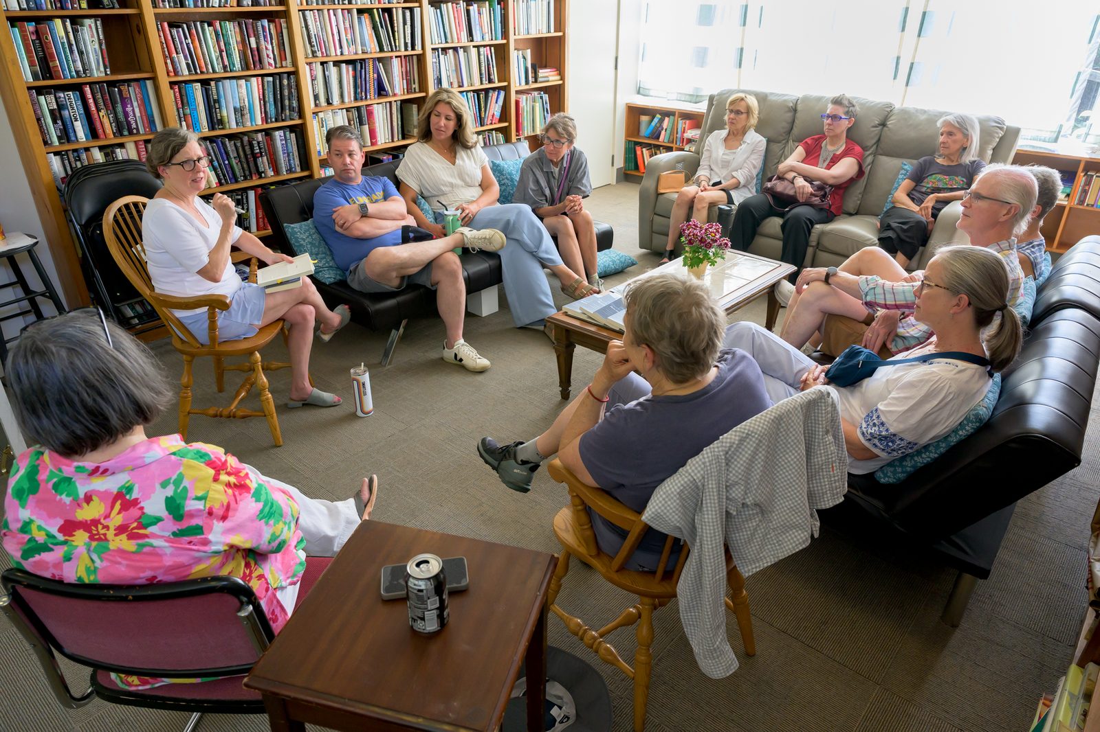 Elizabeth de Veer, book in hand at left, leads a circle discussion in a book-lined room.