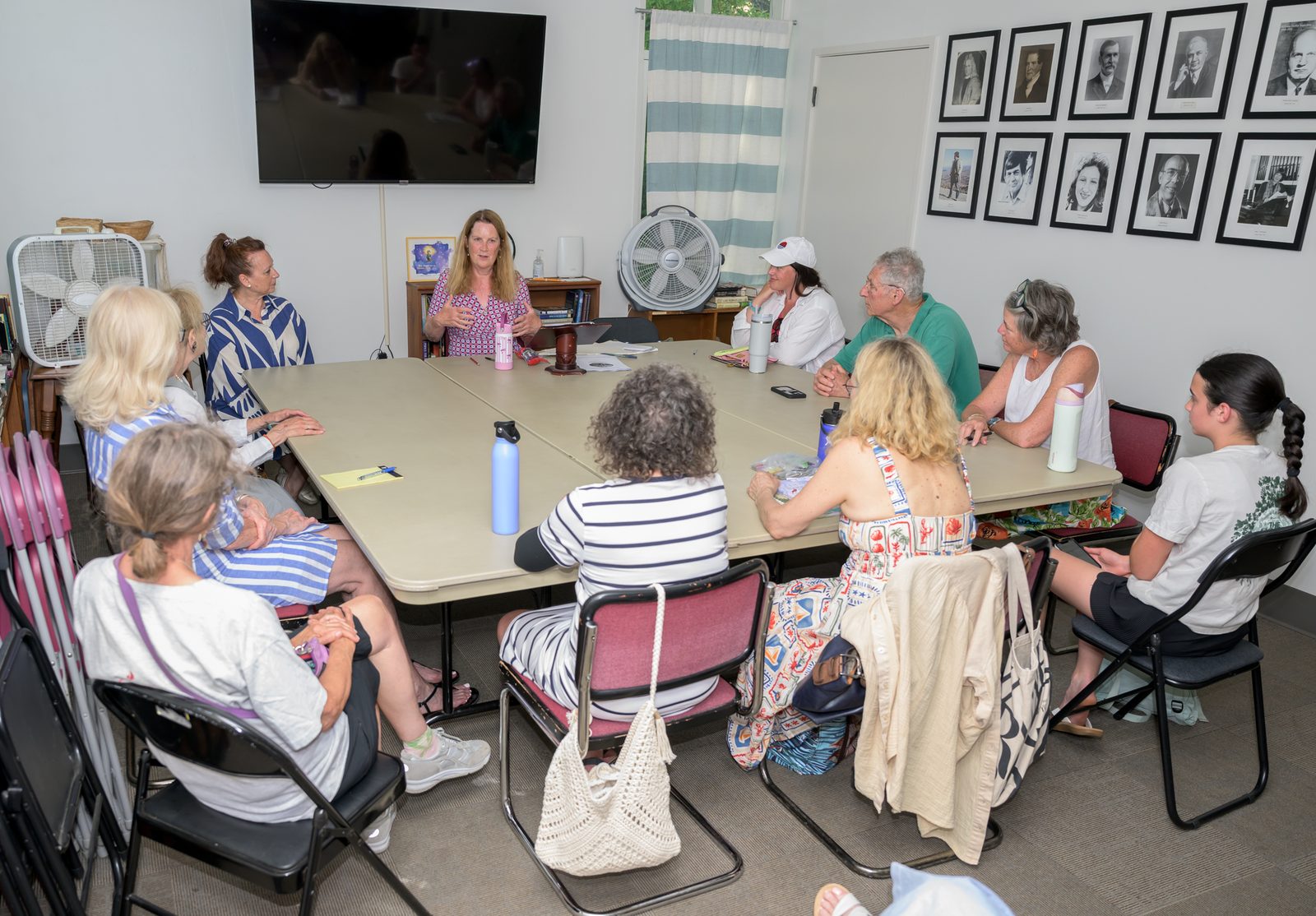 Áine Greaney gestures as participants of all ages gather around folding tables for her writing workshop.