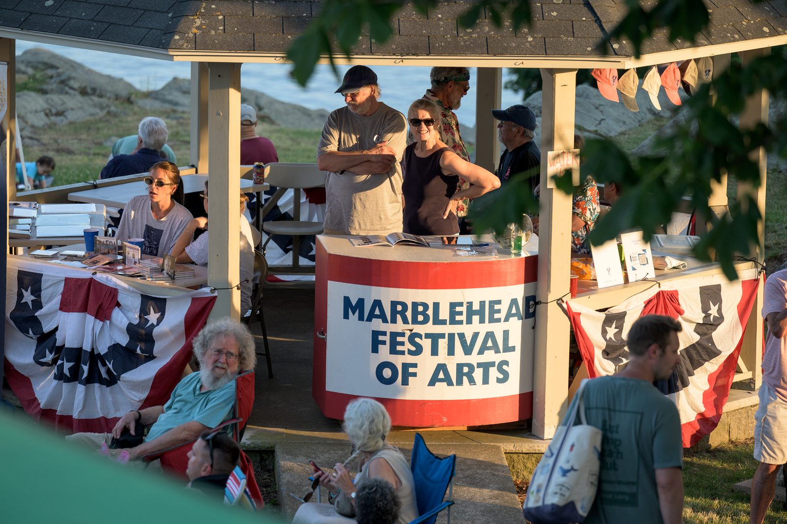 Volunteers staff the festival information booth as concertgoers gather along the waterfront.