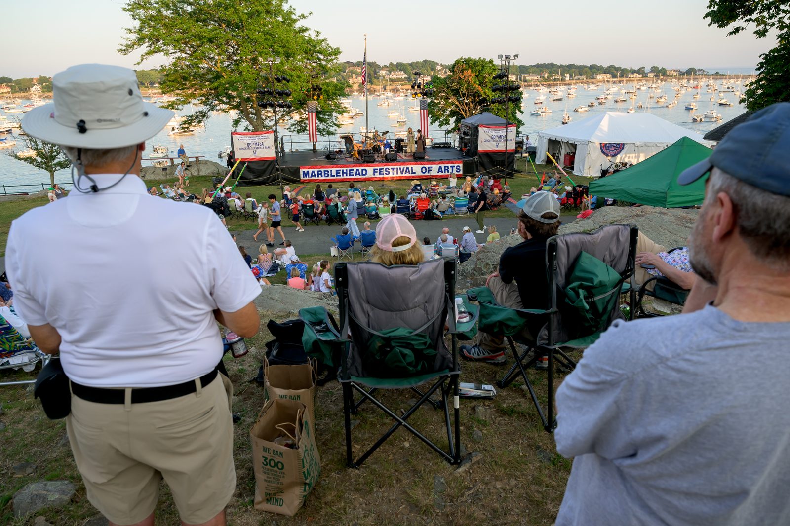 Spectators watch from the rocky high ground as a band performs against the moored fleet.