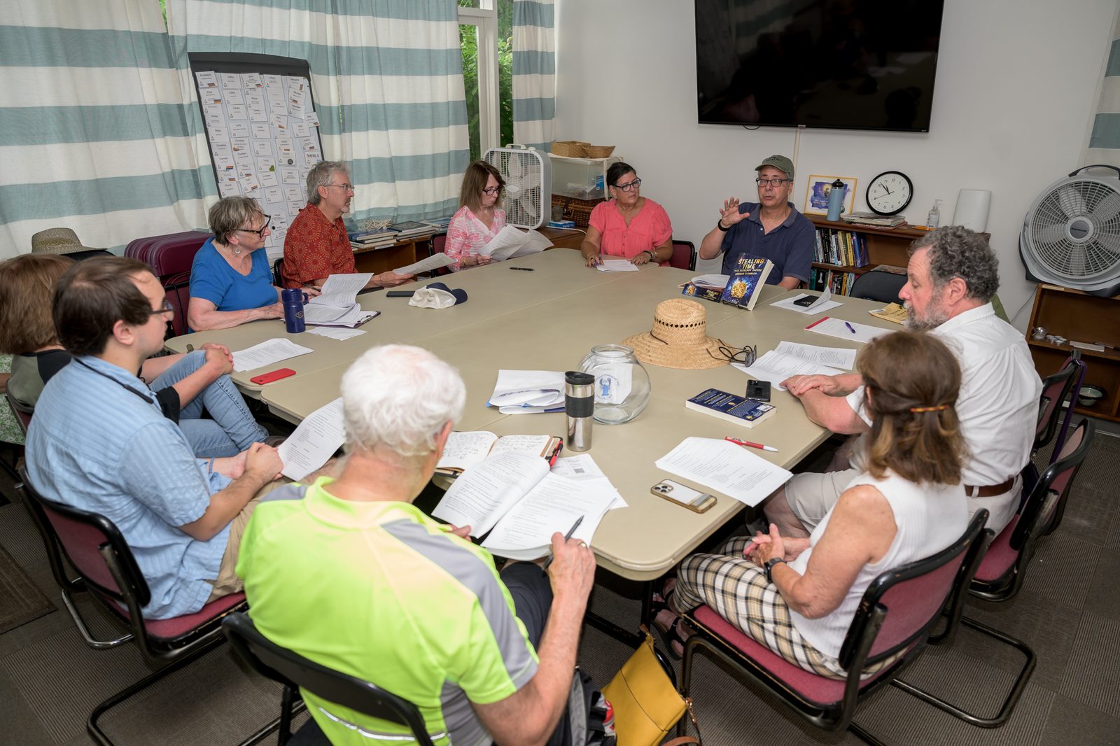Norman Birnbach leads writers through printed manuscripts around a shared table during a workshop.