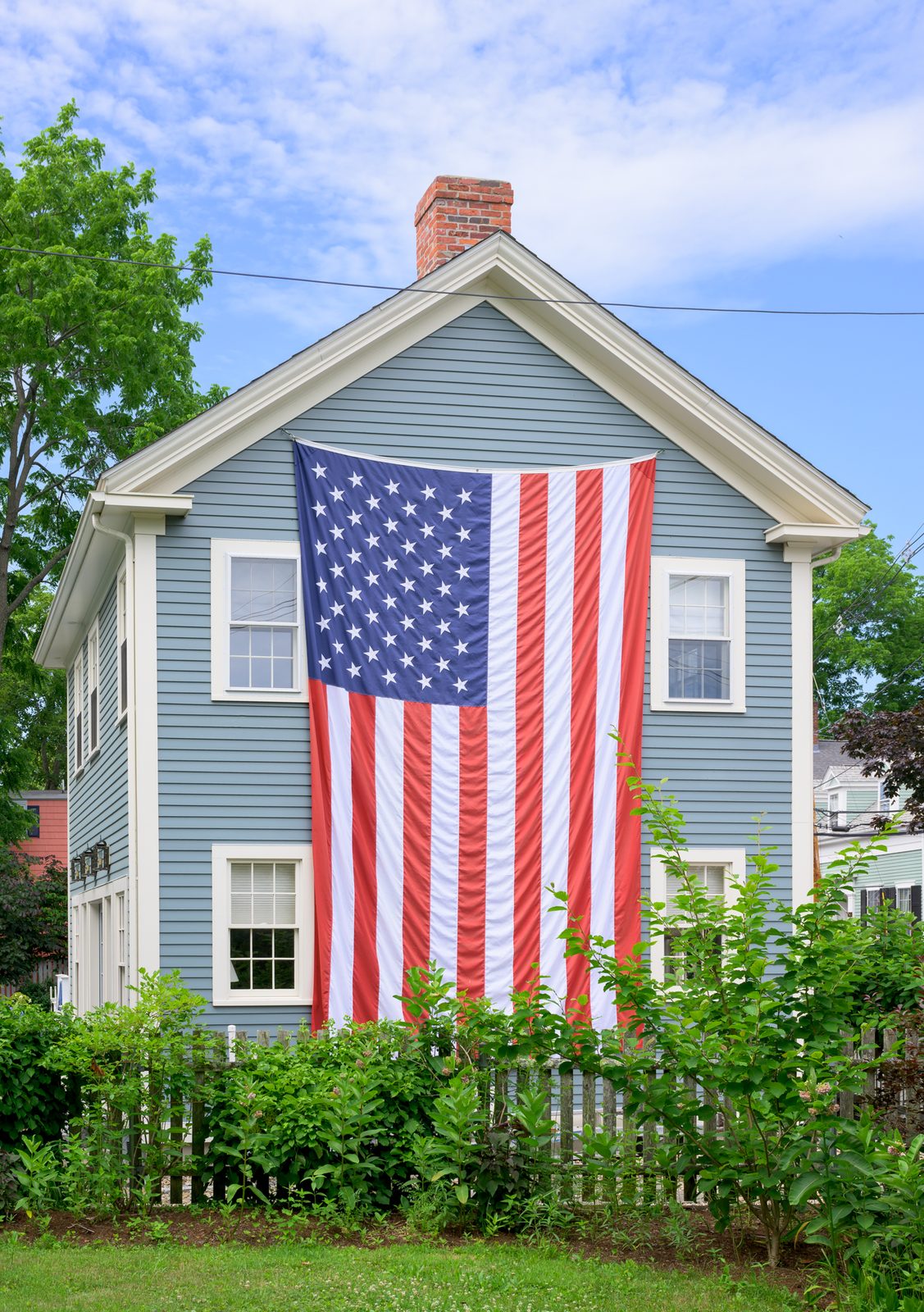A two-story American flag drapes the gable of a Marblehead home during festival week.