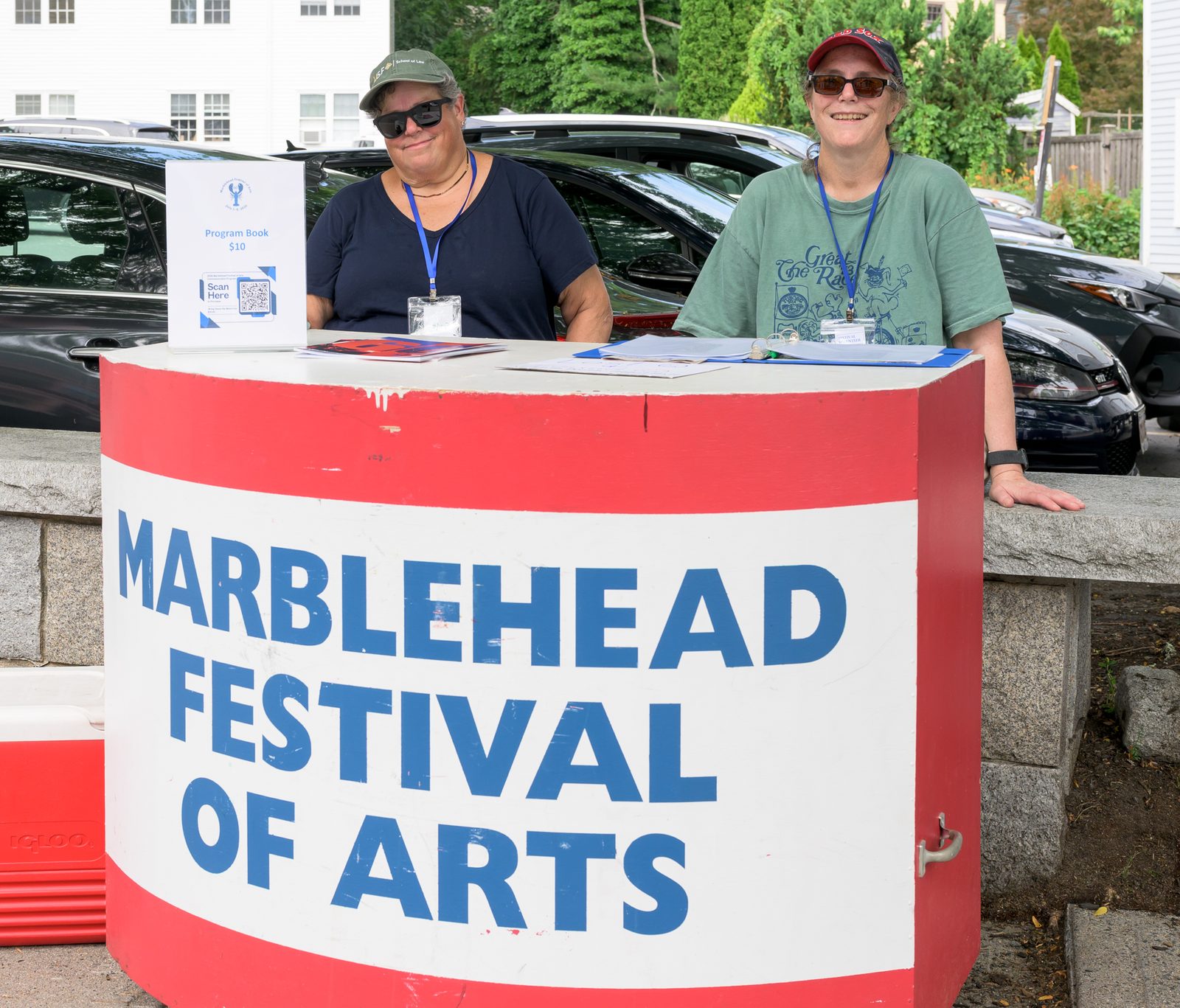 Volunteers greet visitors and sell $10 program books at the festival information kiosk.