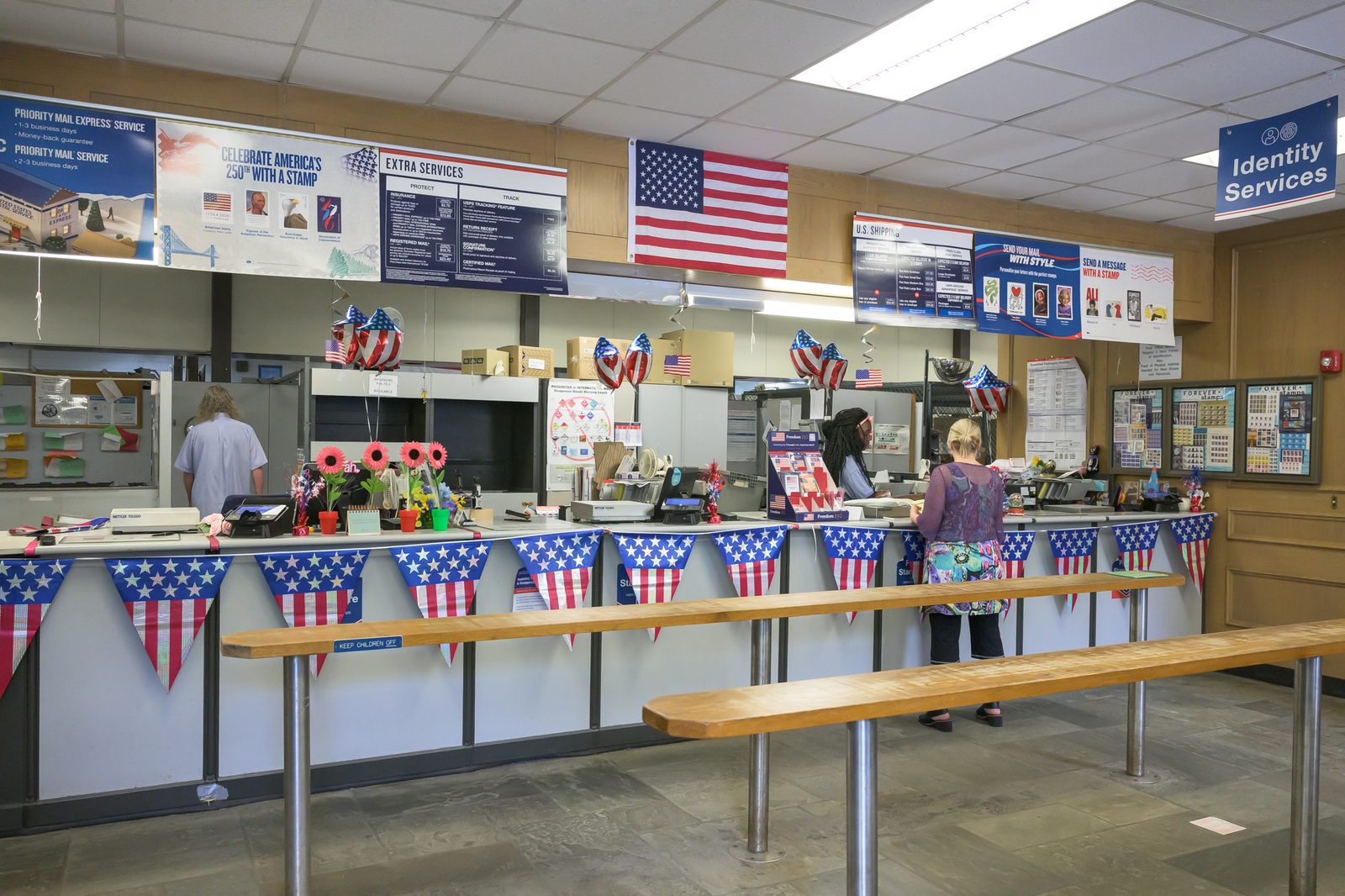 Flag bunting, balloons and a banner promoting America’s 250th-anniversary stamps decorate the counter inside the post office.