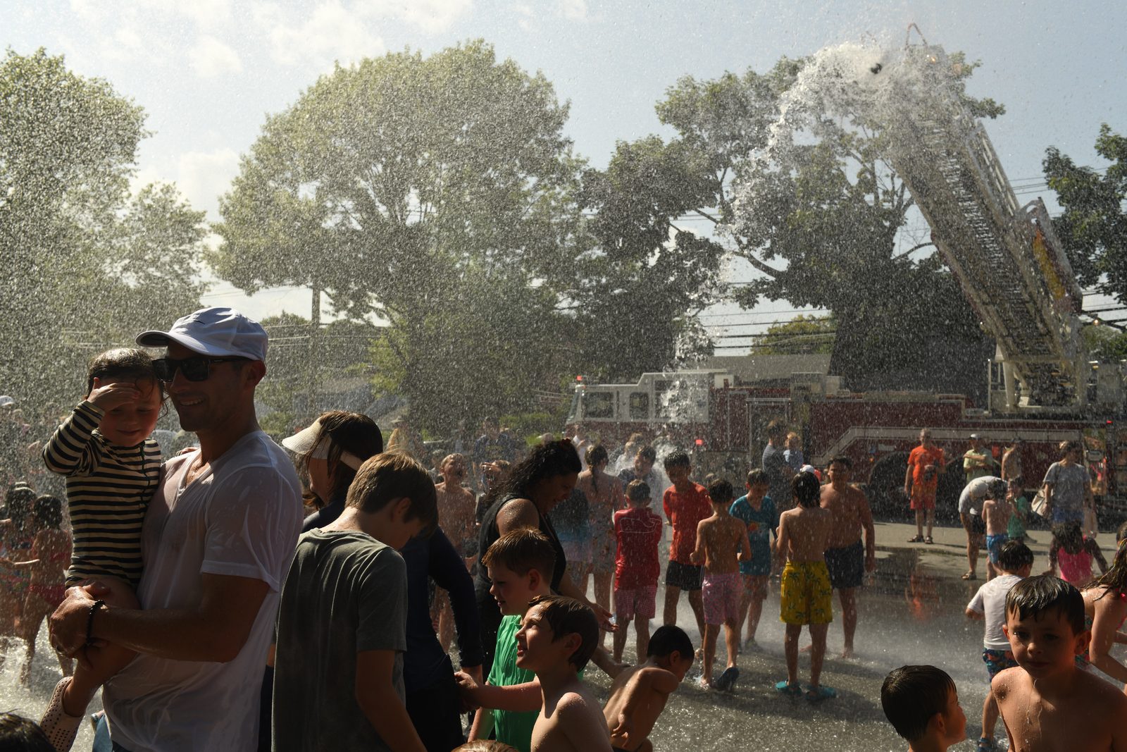 A father lifts a small boy onto his shoulders at the edge of the crowd.