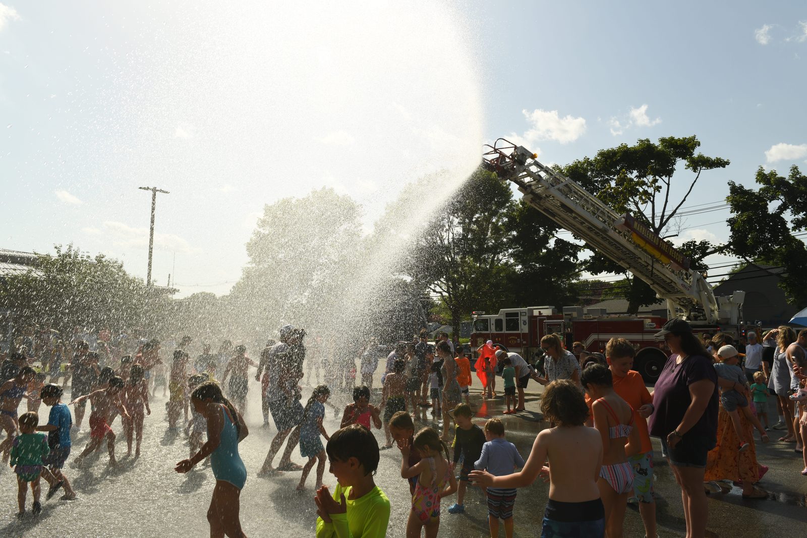 Backlit by the afternoon sun, the spray drifts down over the crowd.