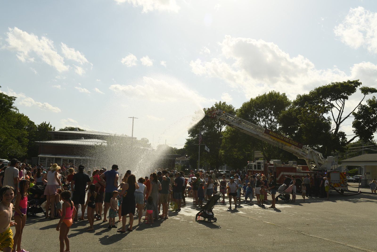 The aerial ladder sends an arc of water over a street packed with families during the July 2 heat.