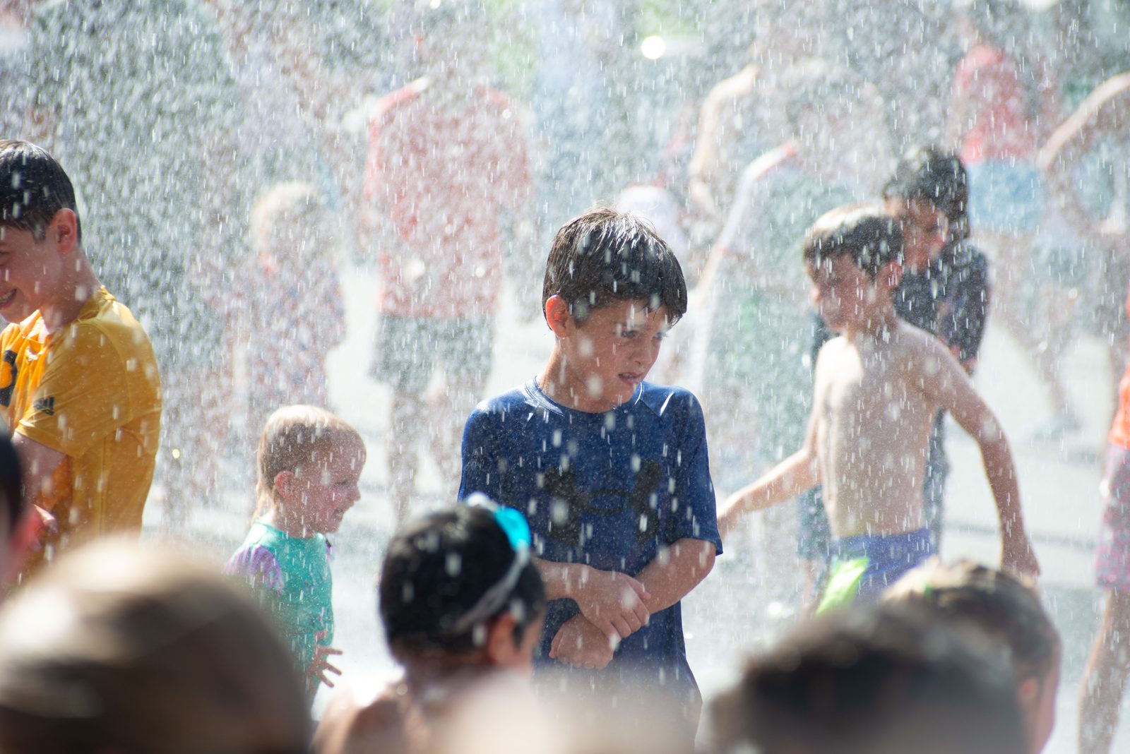 A boy shivers and grins in the cold mist.