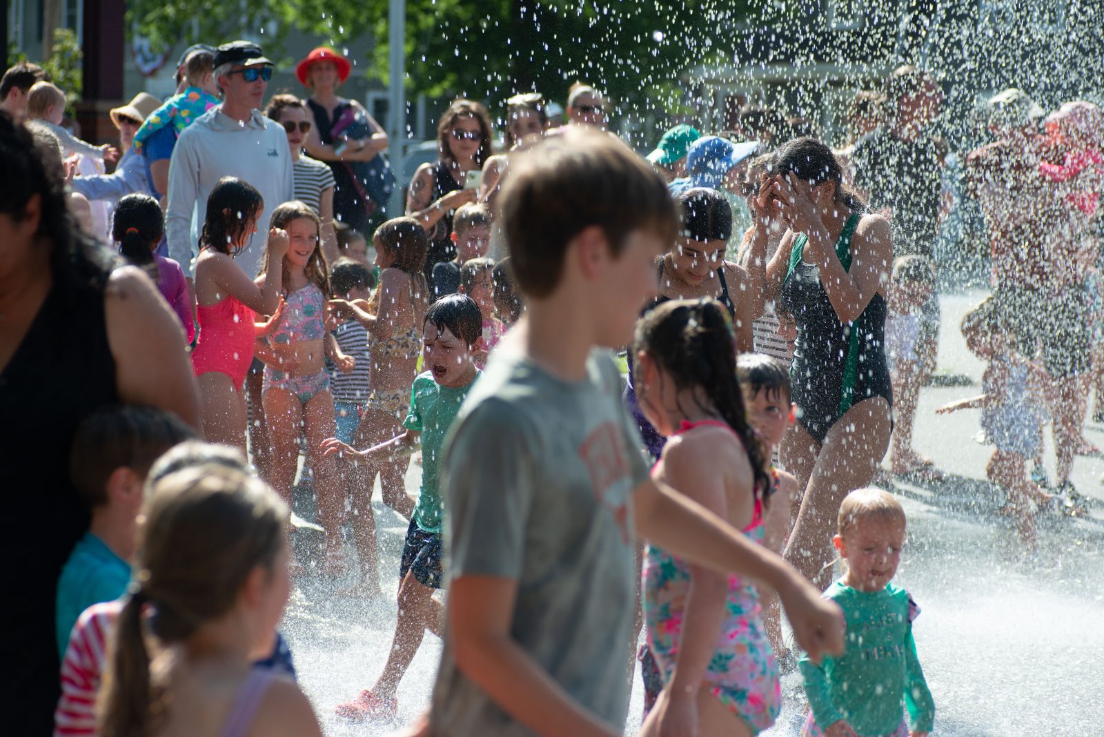 Children thread through the crowd under the spray.