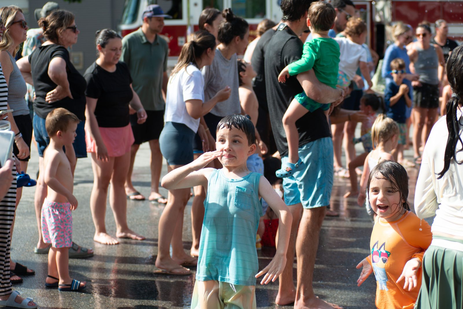 A boy and a girl in teal light up as the water comes down.