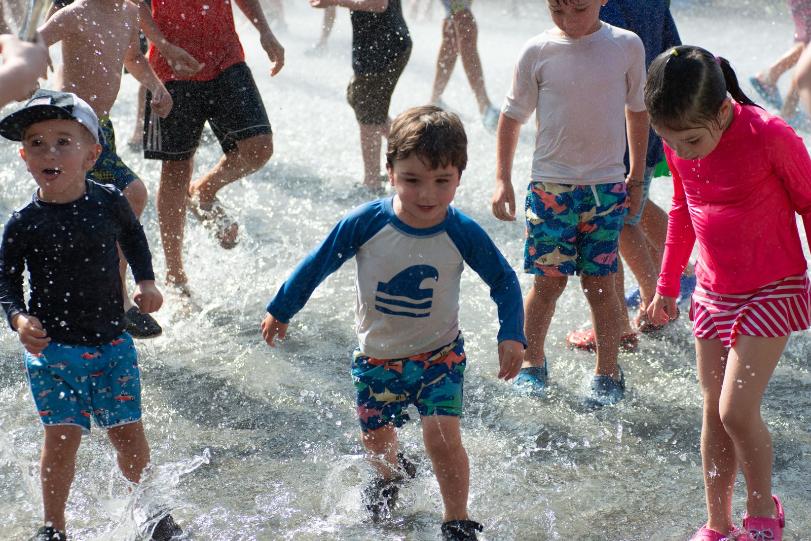 Children splash toward the camera through the runoff.