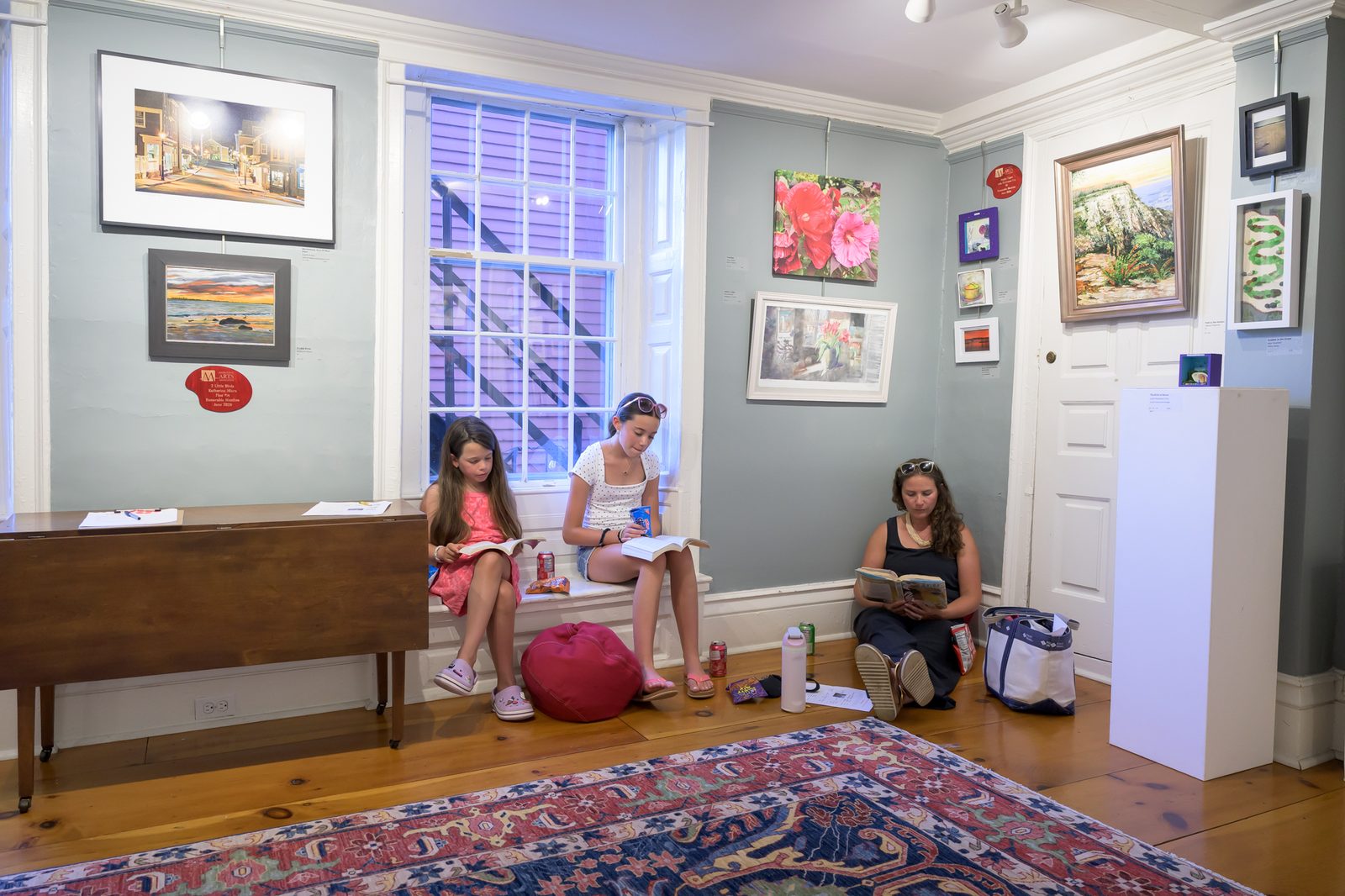 Young visitors settle in to read among the framed work, out of the afternoon heat.