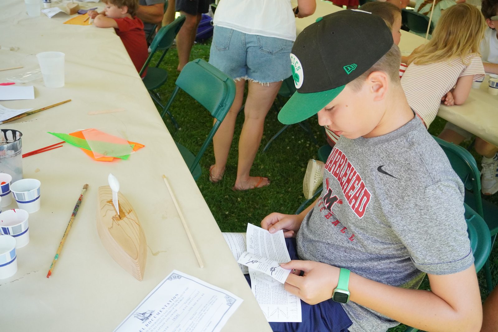 A boy in a Marblehead cap reads the boat-building instructions.