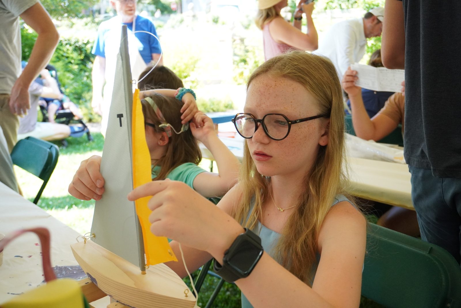 A girl rigs a paper sail onto her finished hull.
