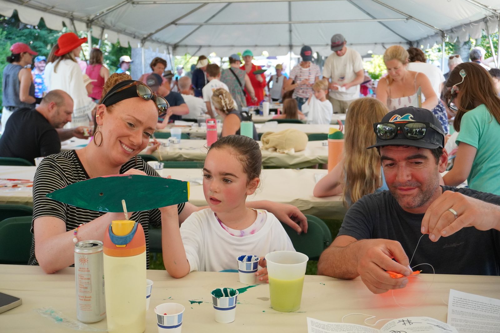 A family shows off a green-hulled boat at the Festival of Arts boat-building workshop in the garden of the Jeremiah Lee Mansion.