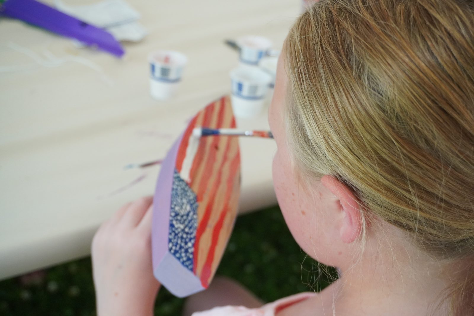 A builder paints the stars and stripes onto her boat.