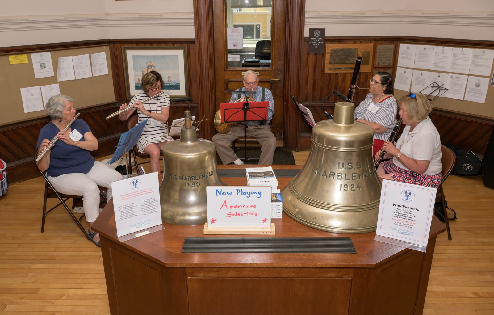 The Windjammers, a woodwind quintet from the North Shore Chamber Music Society, play ‘Americana Selections’ in the foyer of Abbot Hall, framed by the bells of the U.S.S. Marblehead — one cast in 1893, the other in 1924.