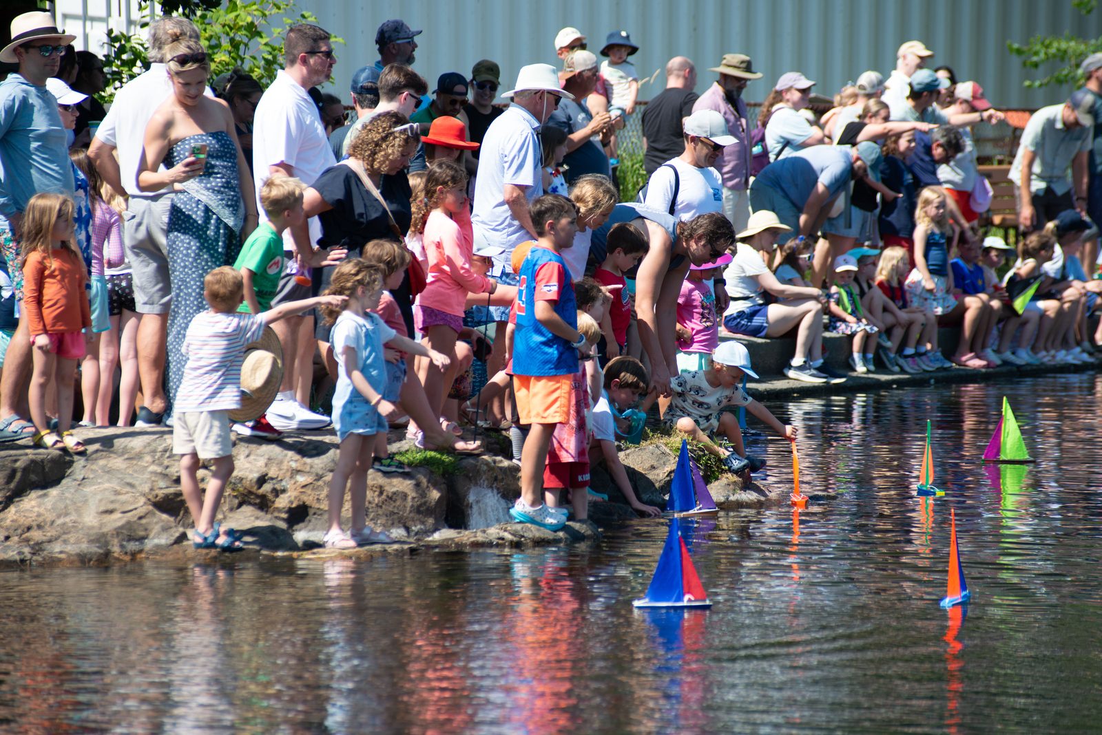 The crowd rings Redd’s Pond, elbow to elbow along the granite, for the festival’s smallest regatta.