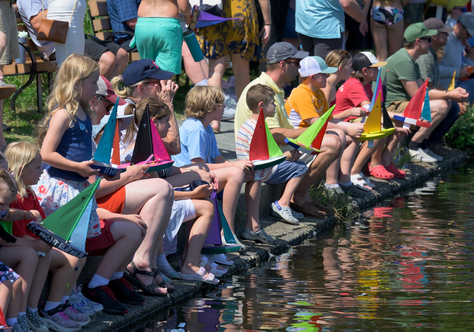 Children line the granite rim of Redd’s Pond, hand-built sloops in their laps, waiting for a turn on the water.
