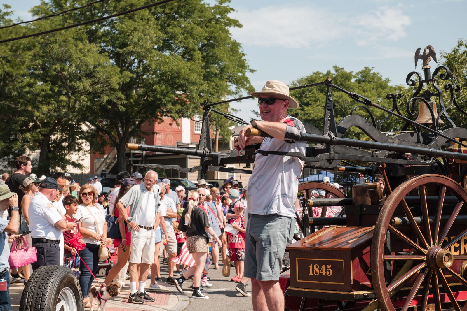 A marcher rings the bell of an 1845 hand-pumper fire engine as the parade passes.