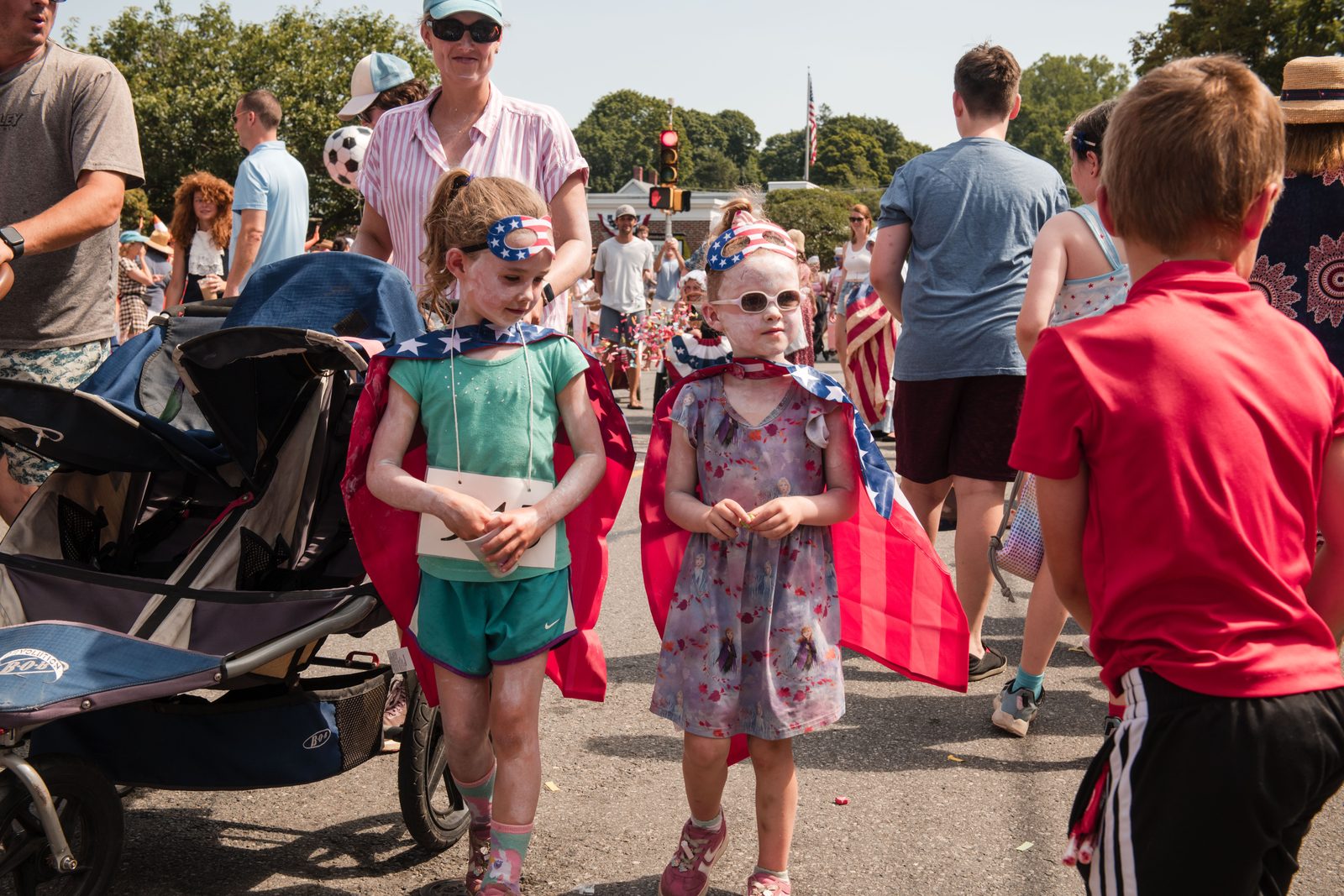 Two girls in flag capes and face paint walk the parade route together.