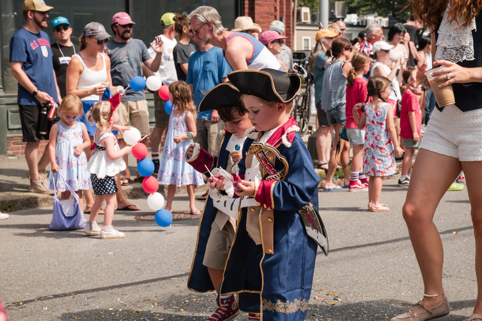 Two small boys in colonial officers’ coats and tricorn hats compare their candy.