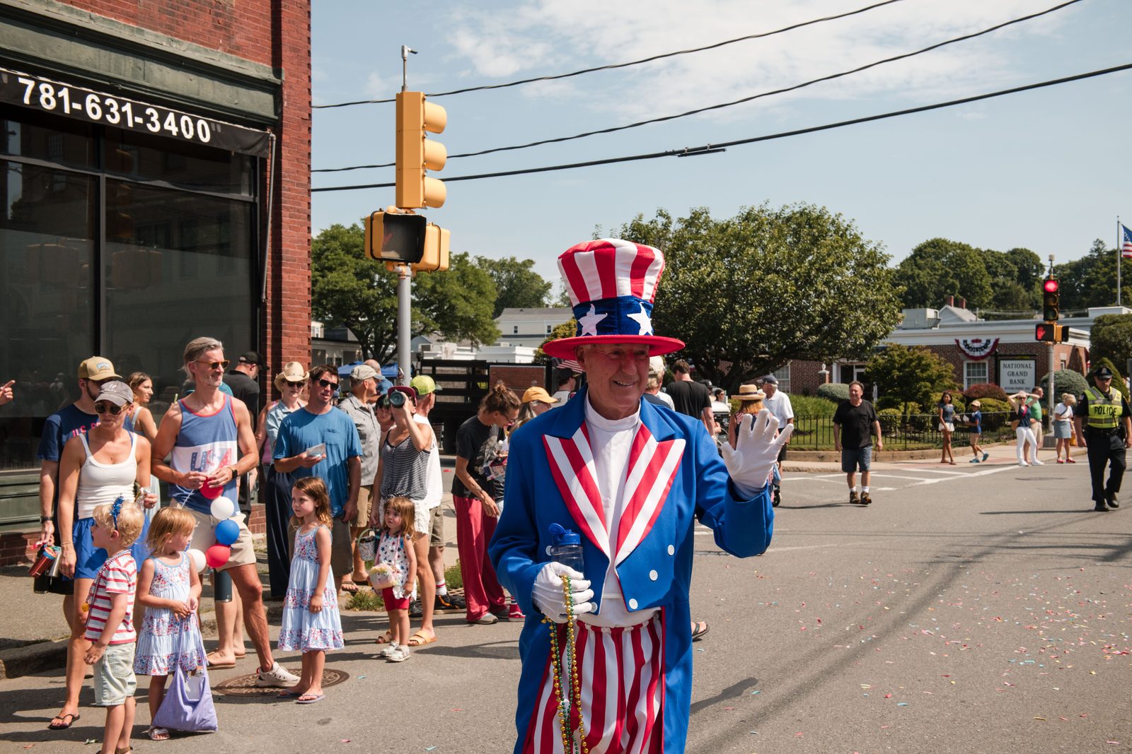 A marcher in a full Uncle Sam costume waves a white-gloved hand to the crowd.
