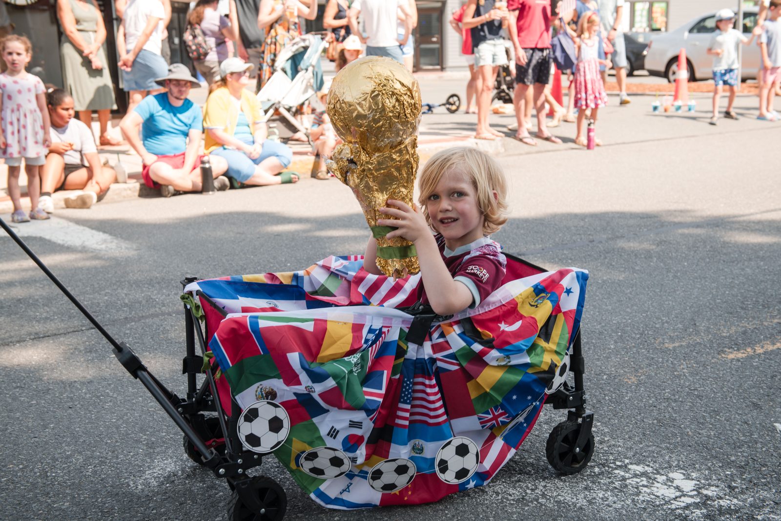 A young marcher hoists a homemade World Cup trophy from a wagon draped in the flags of the world.