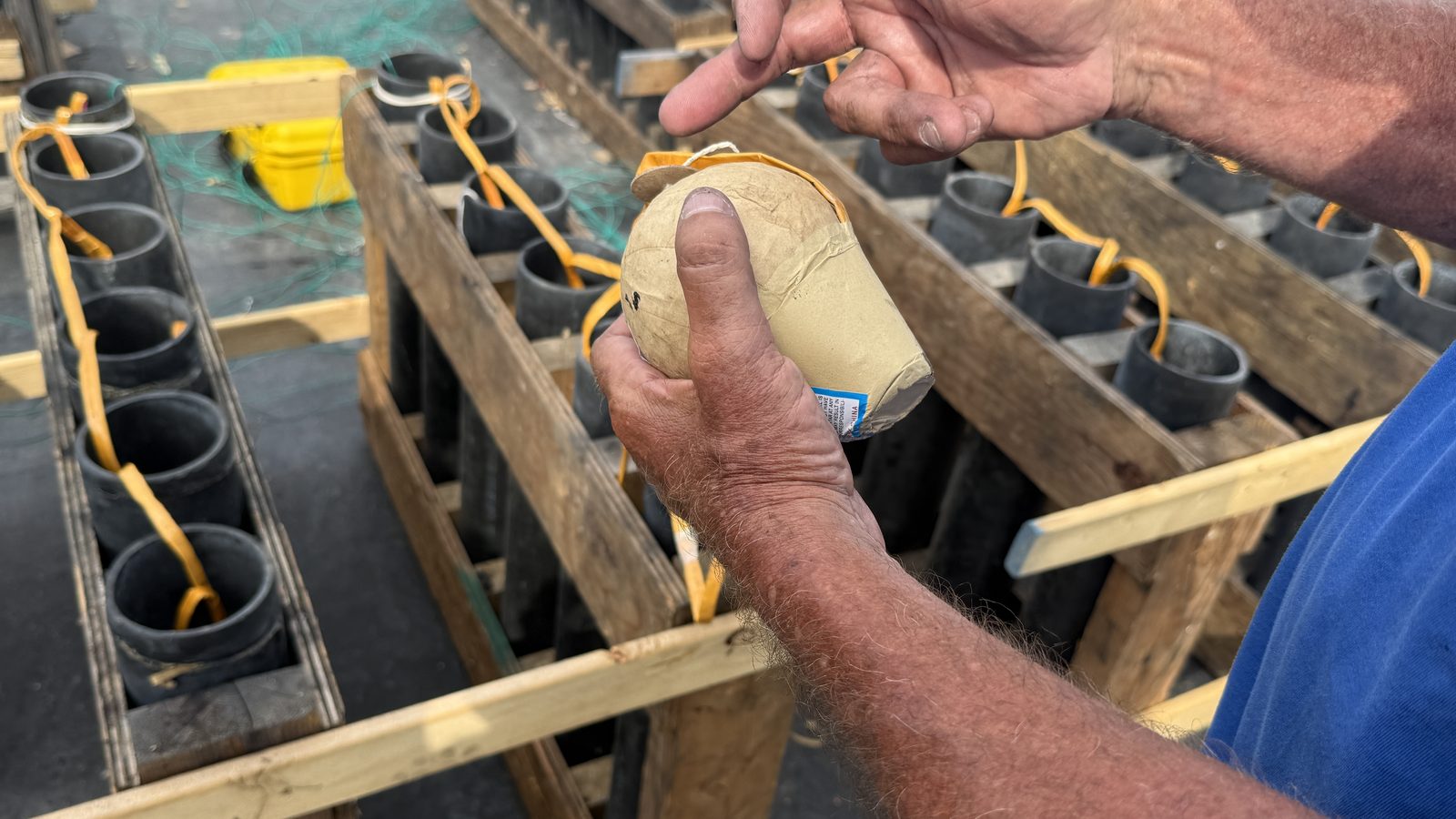 A firework shell is lowered by hand into one of the barge’s mortar tubes.