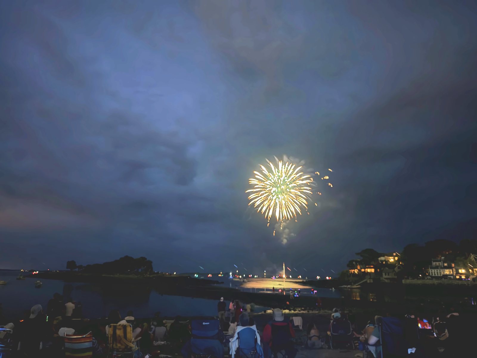 A last golden burst doubles in the still harbor as the show winds down over the moored boats.