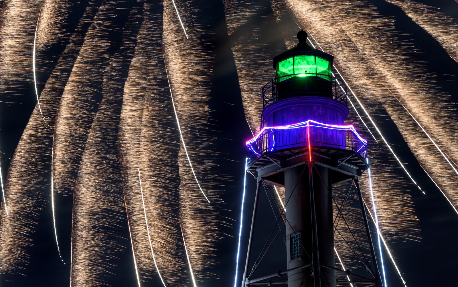 Streamers of gold rain down around Marblehead Light, its lantern glowing green above the harbor.